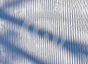 Relief trail in the snow after cleaning the ski slope with a snowcat. Grunge snow background blue stripes