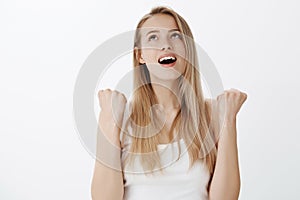 Relieved happy young woman with blond hair breathing out and yelling finally with satisfaction as achieving victory