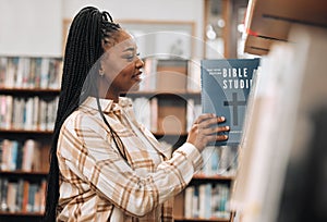 Religion book, education and black woman in a library for research, studying God and knowledge on the bible at college