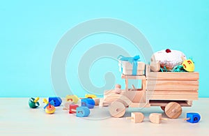religion image of jewish holiday Hanukkah with spinning top and doughnut over wooden car toy and pastel blue background