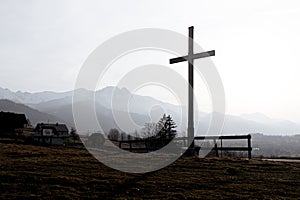 Religion theme, view of catholic cross silhouette, with fantastic sunset and mountains as background. Toned image