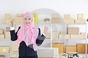 Religious asian muslim woman in blue suit and pink shaft standing and looking at camera with exciting emotion. Business woman
