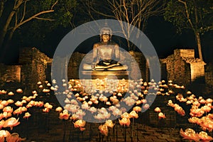 Sitting bronze Buddha statue at night with lighting decoration