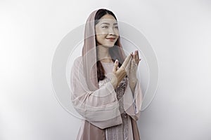 Religious beautiful Asian Muslim girl wearing a headscarf praying to God, isolated by white background