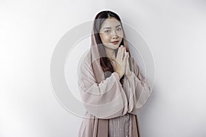 Religious beautiful Asian Muslim girl wearing a headscarf praying to God,  by white background