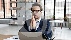 Religious Caucasian businessman pray at workplace in office