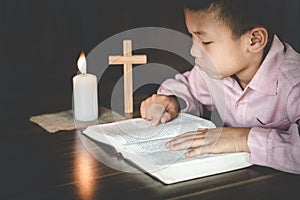 Religious Christian Child  praying over Bible indoors, Religious concepts. Religious beliefs Christian life crisis prayer to god
