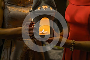 Religious concept. Two females hands holding a burning candle in