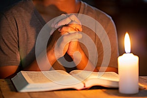 Religious concepts, The young man prayed on the Bible in the room and lit the candles to illuminate