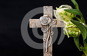 Ornate cross with tulip flowers on a dark background. Condolence card. Empty place for emotional sentimental quote.