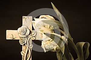 Isolated ornate religious cross with a flower on a dark background. Moment of grief at the end of a life. Last farewell.