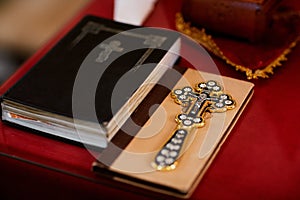 Religious items, bible and gold cross prepared for a ceremony, inside a Christian Orthodox Church. selective focus