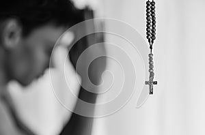 Religious man in prayer with his rosary cross neckalace, at hime.
