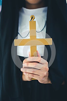 Religious nun in religion concept. Hands praying to the GOD while holding a crucifix symbol . Nun holding a cross in his hands.