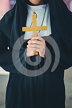 Religious nun in religion concept. Hands praying to the GOD while holding a crucifix symbol . Nun holding a cross in his hands.