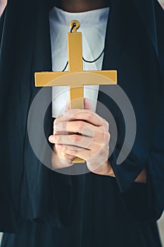 Religious nun in religion concept. Hands praying to the GOD while holding a crucifix symbol . Nun holding a cross in his hands.