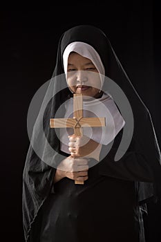 Nuns praying to the GOD while holding a crucifix symbol on black background