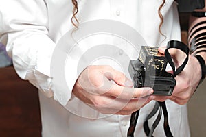 A religious orthodox with arm-tefillin on his left hand prays A jewish man is preparing the tefillin