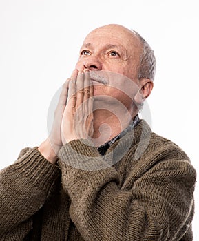 Religious senior man praying to God in studio