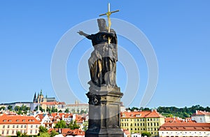 Religious statue on the edge of famous Charles Bridge in Prague, Czech Republic. Prague Castle and historical old town in