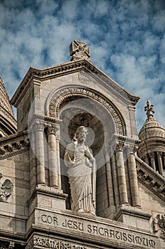 Religious stone statue detail and decoration at the Basilica of Sacre Coeur facade in Paris.