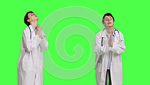 Religious woman physician praying to jesus christ against greenscreen