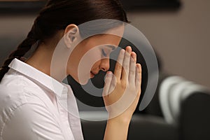 Religious young woman with clasped hands praying