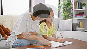 Relishing mother-daughter bond, sitting together at home, drawing intimate expressions on notebook in the quietude of their living