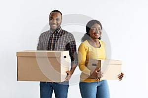 Relocation Concept. Cheerful Black Spouses Carrying Cardboard Boxes And Smiling At Camera