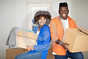 Relocation Concept. Cheerful Black Spouses Carrying Cardboard Boxes And Smiling At Camera