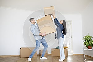 Relocation Concept. Happy Young Couple Packing Things While Moving To New Home