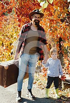 Relocation and nomadic way of life. Father with suitcase and his son. Bearded dad telling son about travelling. Traveler