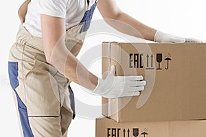 Relocation services concept. Mover`s hands In uniform carrying cardboard Box. Loader puts cardboard boxes