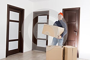 Relocation services man with cardboardboxes. Worker transporting things in the apartment. Moving to a new house concept