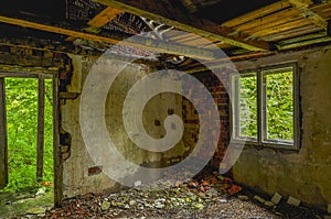 Remains of abandoned damaged and destroyed house interior with collapsed roof and wal.