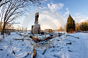 Remains of a burned down house with a brick oven in the middle of a snowy nature