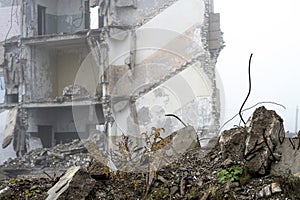 The remains of concrete fragments of gray stones on the background of the destroyed building in a foggy haze