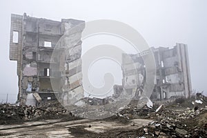 The remains of concrete fragments of gray stones on the background of the destroyed building in a foggy haze