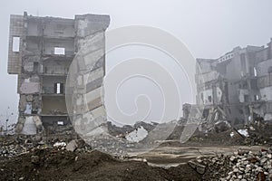 The remains of concrete fragments of gray stones on the background of the destroyed building in a foggy haze