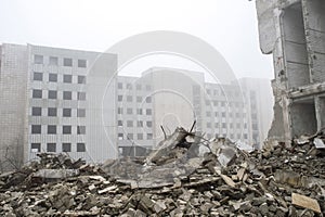 The remains of concrete fragments of gray stones on the background of the destroyed building in a foggy haze