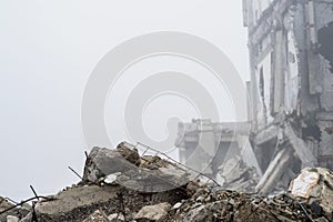 The remains of concrete fragments of gray stones on the background of the destroyed building in a foggy haze. Copy space