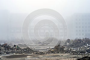 The remains of concrete fragments of gray stones on the background of the destroyed building in a foggy haze. Copy space
