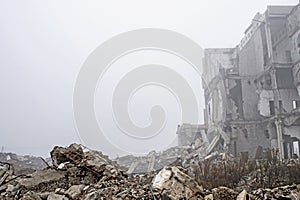 The remains of concrete fragments of gray stones on the background of the destroyed building in a foggy haze. Copy space