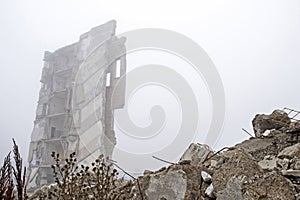 The remains of concrete fragments of gray stones on the background of the destroyed building in a foggy haze. Copy space