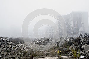 The remains of concrete fragments of gray stones on the background of the destroyed building in a foggy haze. Copy space