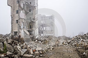 The remains of concrete fragments of gray stones on the background of the destroyed building in a foggy haze. Copy space