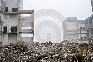 The remains of concrete fragments of gray stones on the background of the destroyed building in a foggy haze. Copy space