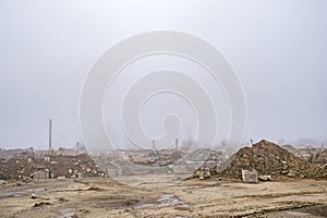 The remains of a large concrete building in the misty haze in the form of fragments of piles and piles of stones