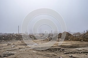 The remains of a large concrete building in the misty haze in the form of fragments of piles and piles of stones