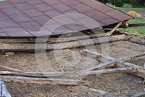 The remains of an old, destroyed metal roof lie on the ground after the demolition of the barn. Day